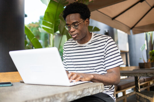 Man studying on laptop in a cozy outdoor cafe setting