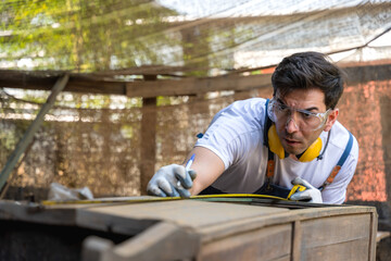 Carpenter man using measuring tape working in carpentry workshop