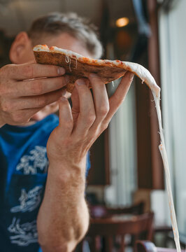 Man enjoying hot cheese pizza in a Brooklyn restaurant