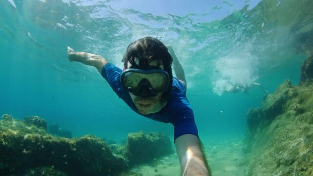Man snorkeling and diving in the ocean near the beach, enjoying summer vacations and adventure trip