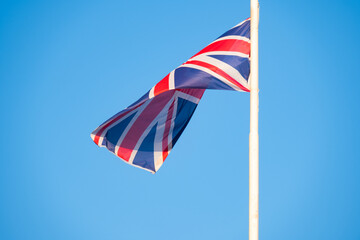 Union Jack flag soars against backdrop clear blue sky, United Kingdom's heritage, resilience, and...