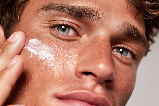 Young man applying facial cream. Male skincare routine, moisturizing face and taking care of skin in morning or evening, represeting a healthy lifestyle
