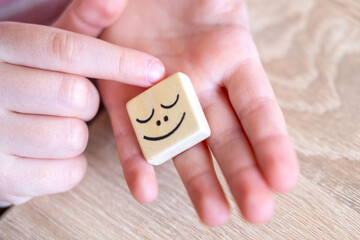 Wooden blocks with emotions, Child's hand playing with wooden blocks, emotional intelligence in...