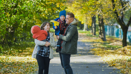 Loving parents hugging children, walking amid colorful autumn foliage, basking in golden sunlight...