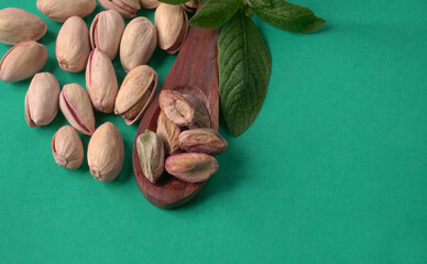 Pistachios or Pista nuts decorated with green leaves. plain background, top view.Flat lay.