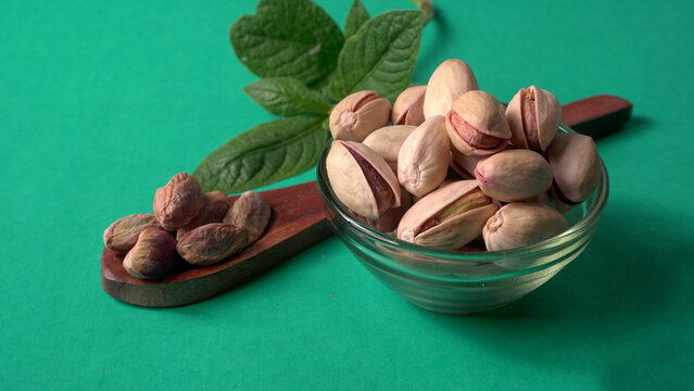 Pistachios or Pista nuts decorated with green leaves. plain background, top view.Flat lay.