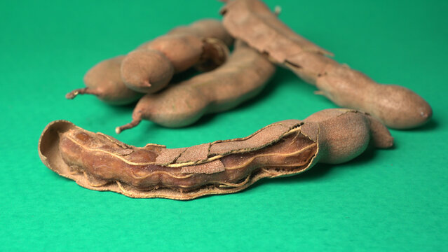 Tamarind fruit with seed isolated on green background with copy space for your text. Top view. Flat lay