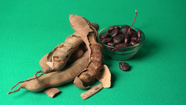 Tamarind fruit with seed isolated on green background with copy space for your text. Top view. Flat lay
