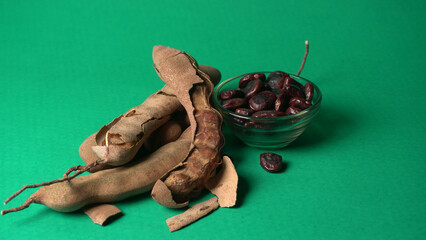 Tamarind fruit with seed isolated on green background with copy space for your text. Top view. Flat lay