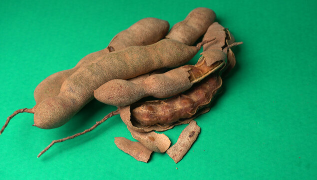Tamarind fruit with seed isolated on green background with copy space for your text. Top view. Flat lay