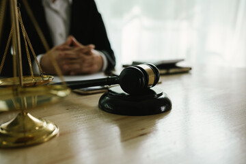 A professional lawyer sits at a desk surrounded by legal books, documents, and a gavel, providing...
