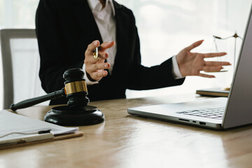 A professional lawyer sits at a desk surrounded by legal books, documents, and a gavel, providing...