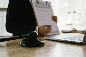 A professional lawyer sits at a desk surrounded by legal books, documents, and a gavel, providing...