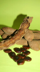 Tamarind fruit with seed isolated on green background with copy space for your text. Top view. Flat lay