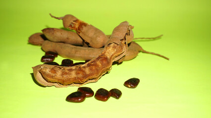 Tamarind fruit with seed isolated on green background with copy space for your text. Top view. Flat lay