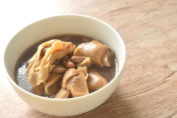 boiled slice Chinese bamboo shoot with pork leg and peanut in clear soup on bowl