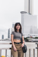 Happy solo southeast asian woman teenager blogger world travel explorer, local cultural experience. Asia tourism concept, wait express boat Chao Phraya river, Bangkok Thailand
