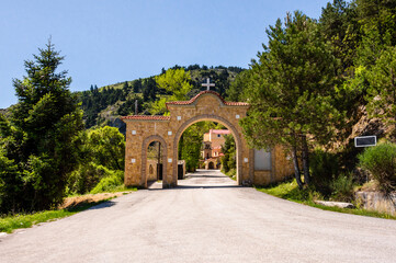 Stone monastery entrance with cross and arch in Trikala, Corinth, Greece, surrounded by green...