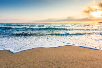 empty beach in the forenoon. beautiful landscape at the black sea. waves washing the sand on the shore. foam on the coast. clouds glowing in morning light. calm summer vacation and travel destination