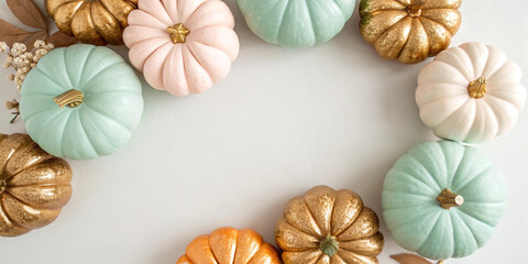 Stylish pastel colored and gold pumpkins forming a decorative frame on a light background, capturing the essence of autumn and halloween with a touch of elegance