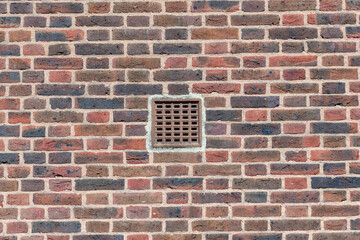 Red brick wall with a ventilation grid