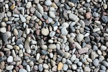 Close-up view of small pebbles creating a natural pattern and texture. Tiny gravel stones in...