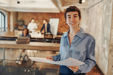 A confident woman presents innovative ideas in a modern office, engaging her team with enthusiasm...