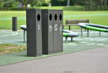 Sorting trash bins in a public park with separate containers for plastic, paper, and glass and...