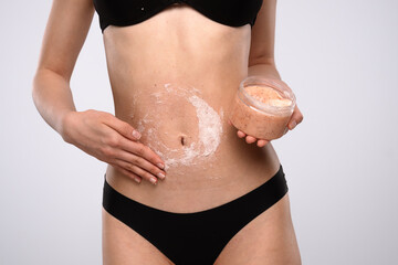 Woman Applying Exfoliating Body Scrub to Her Stomach Skin