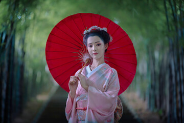 A young Asian Japanese woman in a Traditional Furisode Kimono Yukata dress costume holding a red...