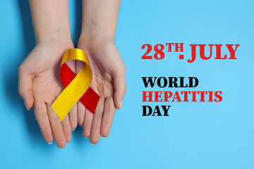 28th july World Hepatitis Day. Woman holding yellow-red awareness ribbon on light blue background, top view