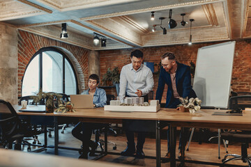 A group of team members enthusiastically discuss innovative project ideas in a stylish, modern...