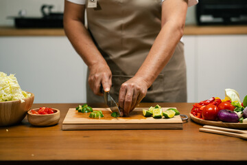 Close-up of man's hand cutting lemon on wooden cutting board in kitchen, preparing for cooking.