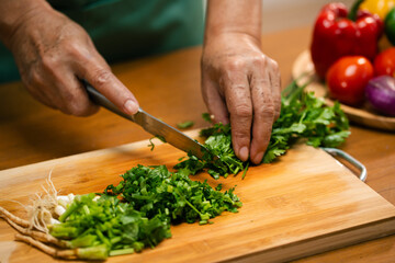 Asian man's hands chopping coriander in the kitchen