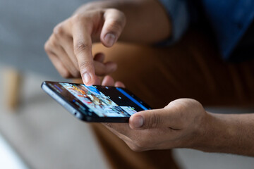 A person uses a smartphone, touching the screen with a finger. Focus is on the hand and device,...