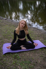 Young woman practicing yoga outdoors in an urban park, combining physical activity with natural surroundings.