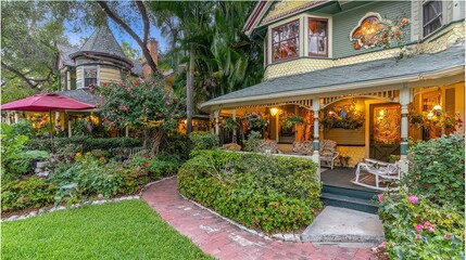 Southern-style home with wrap-around porch, white columns, and rocking chairs, bathed in golden light amid lush greenery. Classic elegance meets 