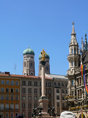 Munich, Marienplatz with the Virgin Mary columns and the golden statue of Holy Mary and Child against the bell towers of the Our lady's cathedral (Frauenkirche) and view of the gothic New Town Hall