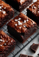 Deliciously Rich Chocolate Brownies Topped with Flaky Sea Salt on a Cooling Rack Surrounded by Chocolate Squares and a Gourmet Presentation