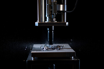 Industrial machine press crushing metal fragments and creating dust particles