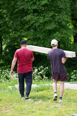 Men carry boards to assemble a gazebo in a lavender field.