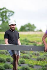 A man helps carry the already assembled floor for the gazebo.