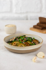 Spicy cucumber salad with sesame seeds, green onion, soy sauce and garlic in a bowl with bread. Vertical orientation.