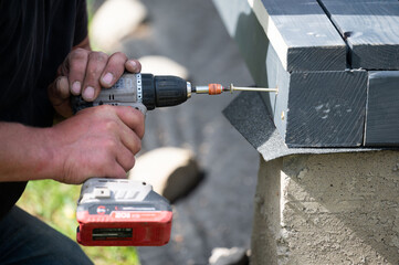 A man is drilling screws into wooden beams