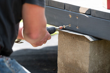 A master carpenter is driving large screws to secure the frame and floor in the gazebo.