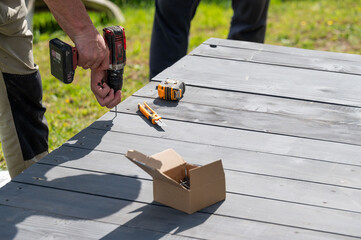 The craftsman uses a screwdriver to tighten the screws that secure the floor to the base of the...