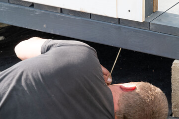 Installation work of a wooden gazebo, the master is screwing screws into the wooden floor.