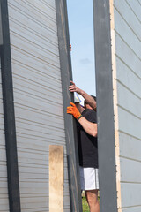 Installing a wall of wooden planks painted white in a gazebo.