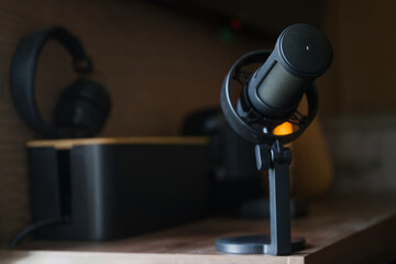 Close-up of a professional condenser microphone mounted on a desk stand in a dimly lit home recording studio, ideal for podcasting, streaming, radio broadcasts. Photo. Selective focus. High resolution