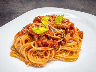 Tomato-meat mixture on spaghetti decorated with green celery leaves